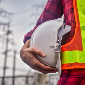 Construction worker holding white safety helmet while wearing high visibility vest—symbolising AS/NZS 4602.1:2024 compliant gear and workwear safety in Australia.