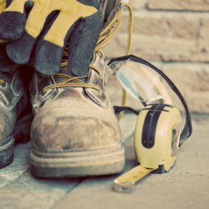 Heavy-duty work boots with gloves, safety glasses, and tape measure – ideal protective gear for construction and trade professionals