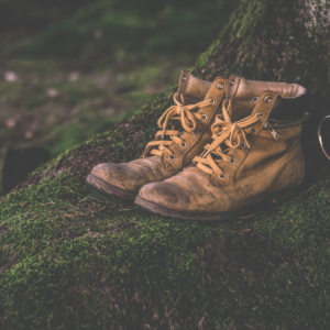 Worn leather work boots on moss-covered ground – durable footwear for outdoor and landscaping professionals