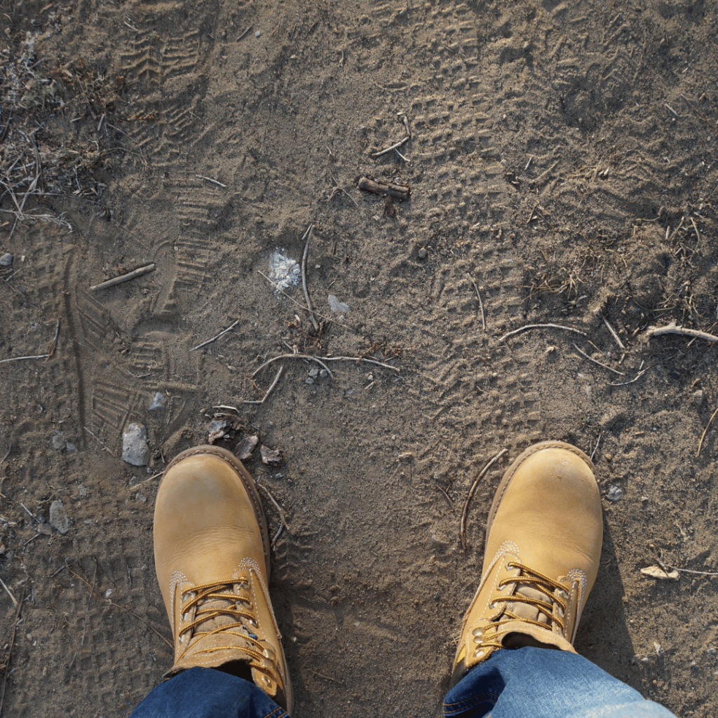 Person wearing tan work boots standing on dirt – rugged footwear built for site durability and grip”